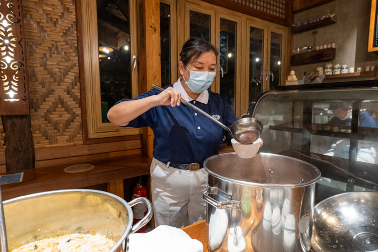 A volunteer serves tang yuan (glutinous rice balls), a symbolic dessert representing family unity in Chinese tradition.