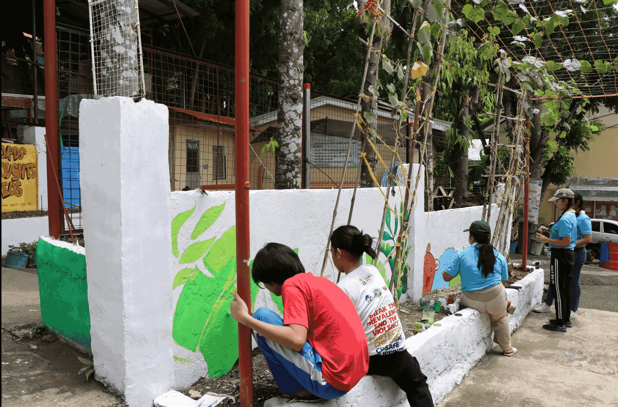 Scholars paint Master Cheng Yen’s Jing Si aphorisms on the wall of Pulpogan National High School / Photo courtesy of Tzu Chi Cebu.
