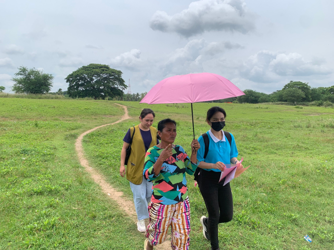 Standing in a sun-drenched field, Andrea Bonife Ibañez (in blue) embodies a dream realized through faith and compassion—a former TB patient-turned-doctor, ready to serve those who need it most in the communities that shaped her journey.