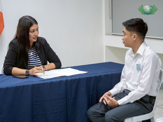 A volunteer interviewer (left) assesses the resumés and answers of interviewed scholars.