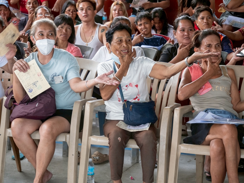 Beneficiary Teresita Alcaraz (front row, center) participates wholeheartedly in the sign language performance of “One Family.”
