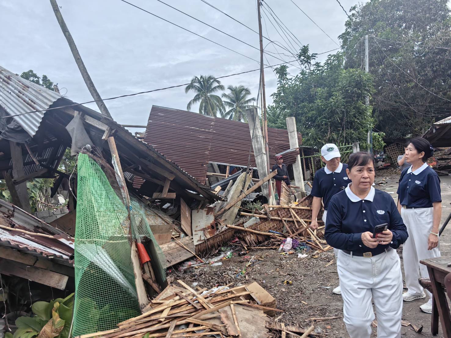 Volunteers walk past a pile of debris where a house once stood. 