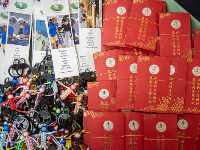 Tokens are given to the beneficiaries, such as the prosthesis keychains, Tzu Chi bookmarks, and red envelopes (angpao) from Dharma Master Cheng Yen, symbols of gratitude and love towards the recipients.