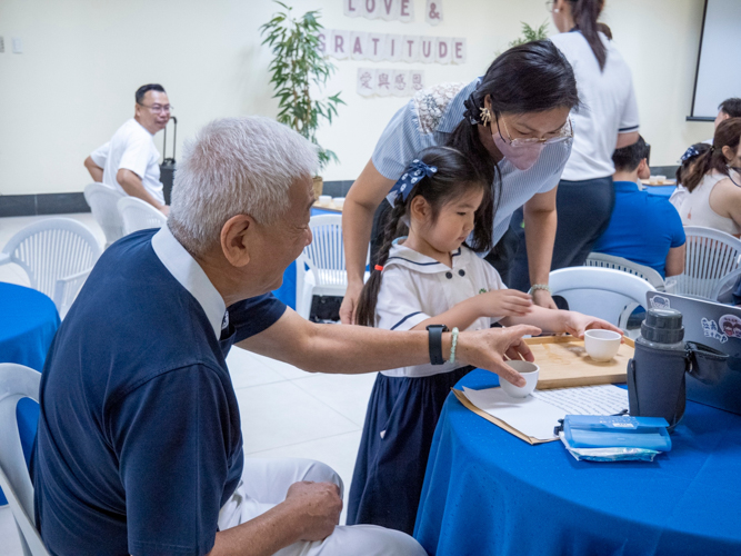 Tzu Chi Philippines CEO Henry Yuñez (left) accepts a cup of tea from Tzu Chi Great Love Preschool student Sephora Hung.