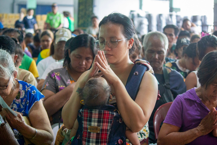 Beneficiary Luz Angelee Rojas joins in prayer.