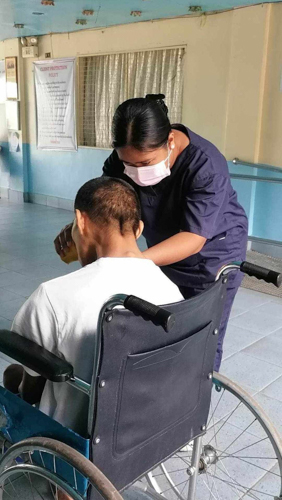 Venus Telecio (in blue uniform) applies her knowledge to a disabled patient with proper care.