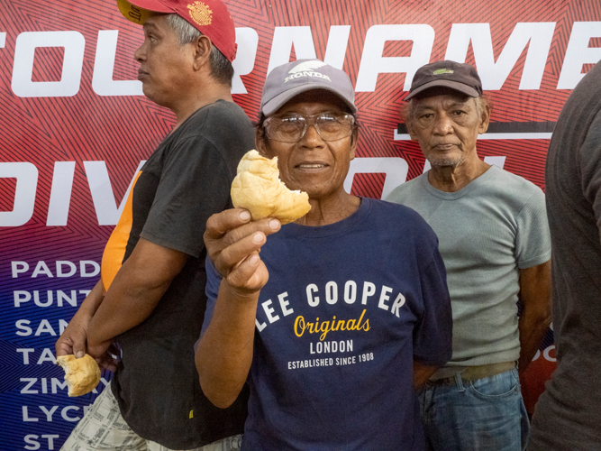 A man smiles as he receives bread from Tzu Chi. 