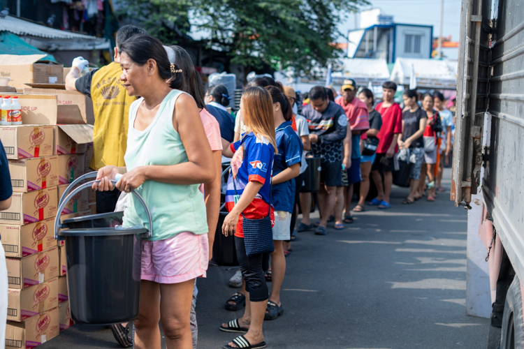 Beneficiaries line up as they claim essential items including clothing, personal hygiene products, cooking supplies, basic kitchenware, and a 10-kg sack of rice.