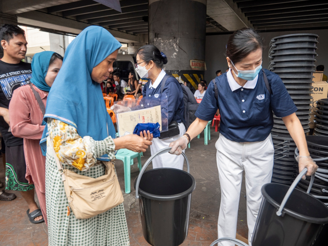 Transcending religious barriers: A Tzu Chi volunteer assists a Muslim beneficiary during relief distribution.