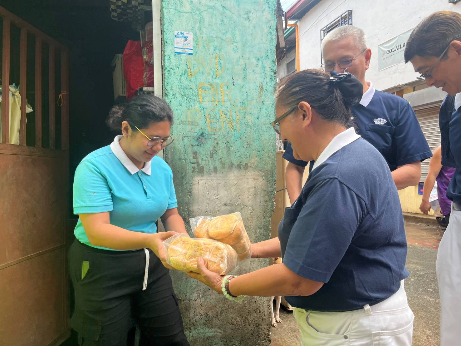 Tzu Chi scholar Maureen Linsangan claims bread from a volunteer. She also received basic provisions, four GI sheets, and other construction materials. 