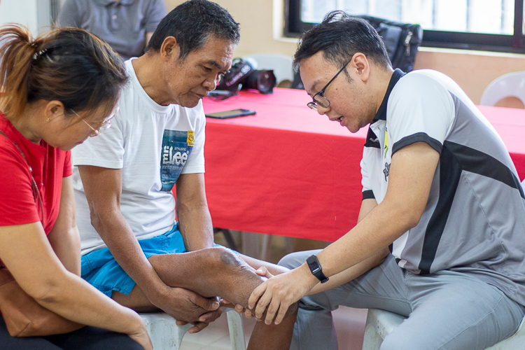 A volunteer physical therapist from Zamboanga City Medical Center checks the condition of a beneficiary’s leg.