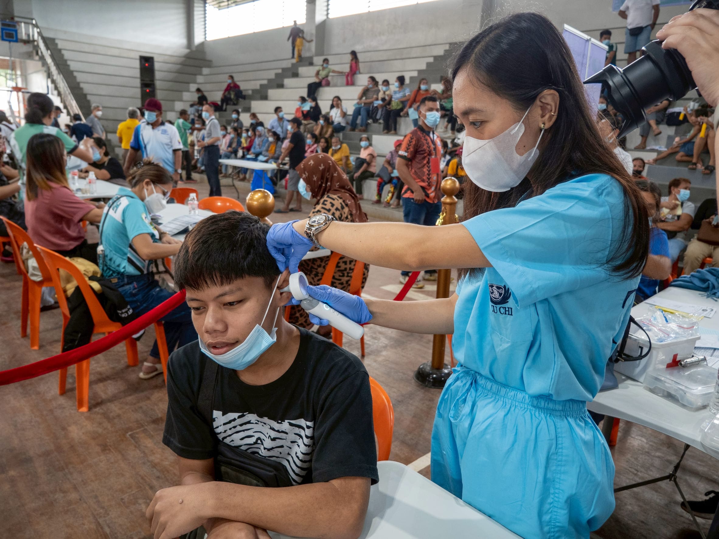 A Tzu Chi volunteer uses an otoscope to check the inner ear of patient John-rell Pandalan. 