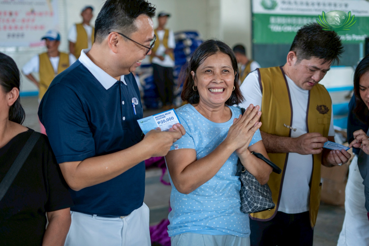 Gina Reyes (in light blue) is grateful to receive the ₱20,000 construction voucher to help rebuild their home.