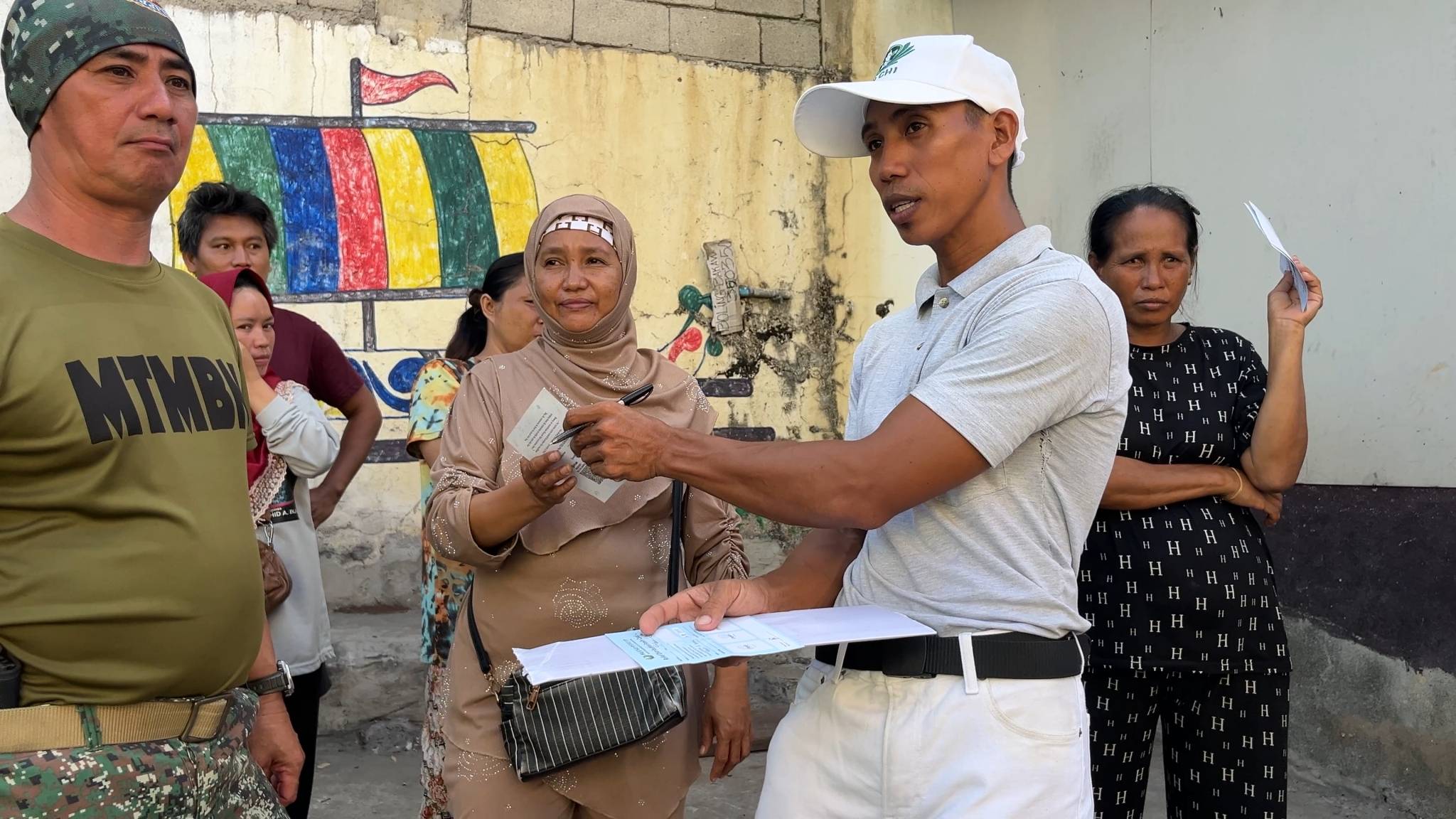 Tzu Chi volunteer Leo Enricoso assists residents by distributing stubs needed to claim relief aid. 