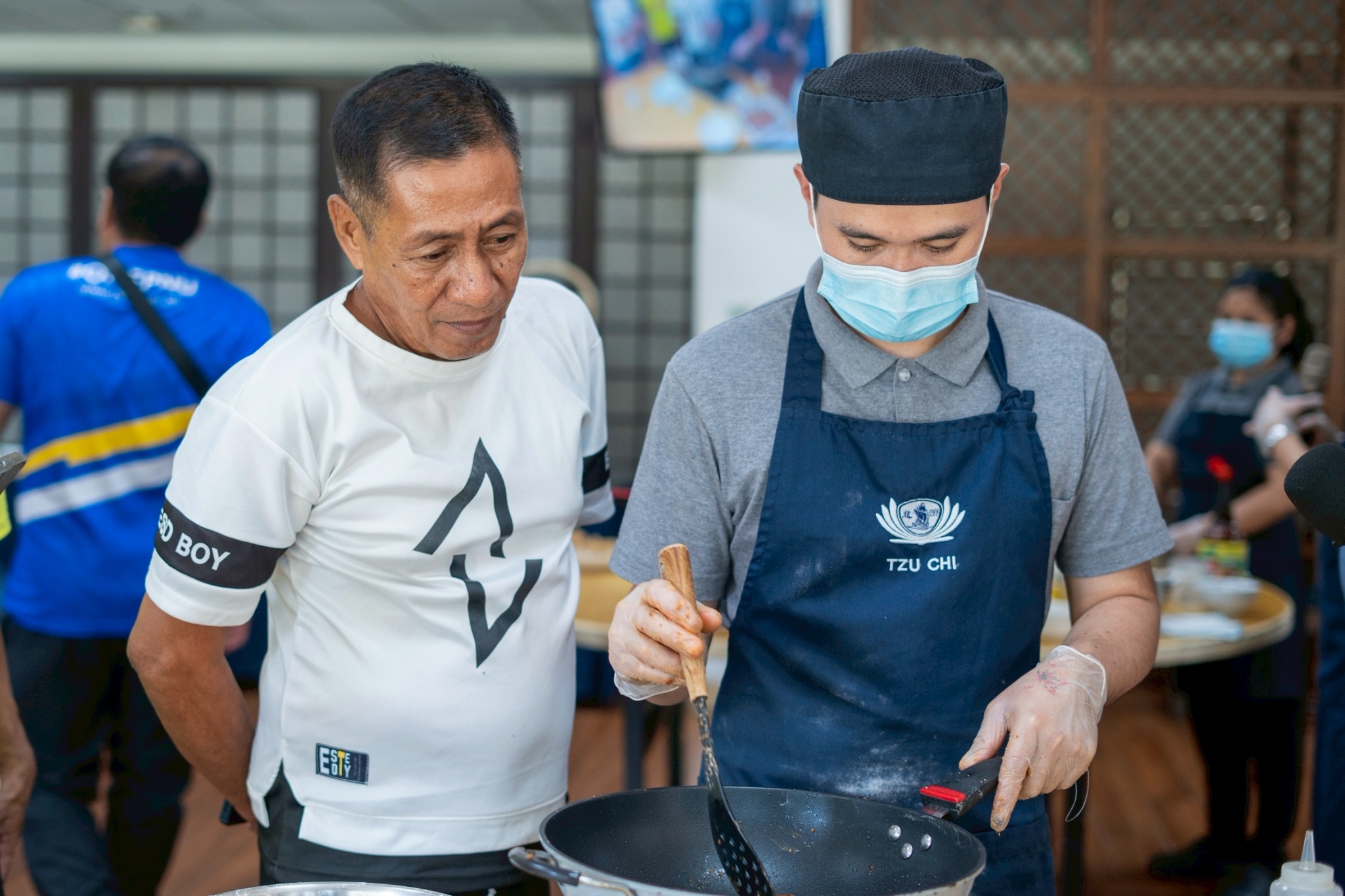 Canteen manager Romulo De Jose (left) closely observes Tzu Chi staff as they prepare the meatless longganisa, which is cooked similarly to its traditional counterpart—first simmered in water, then fried in oil until golden brown.