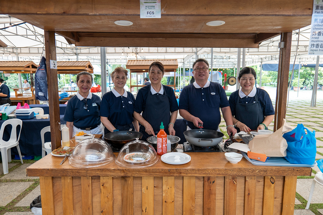 All smiles behind the counter, volunteer vendors pause for a quick photo together while serving up delicious treats for a good cause.