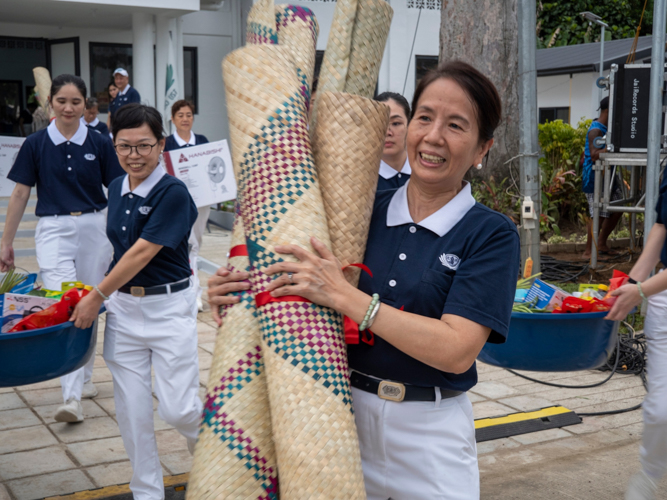 Volunteers all laugh and smile while carrying the housewarming gifts for the residents.