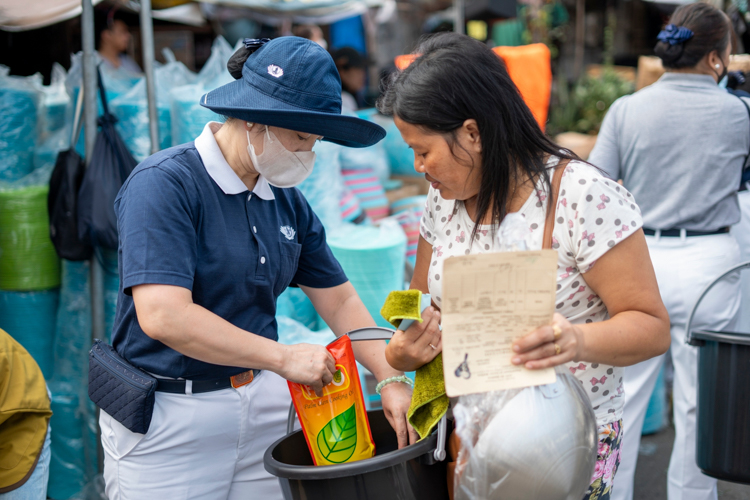 A Tzu Chi volunteer puts cooking oil inside the pail of the beneficiary.