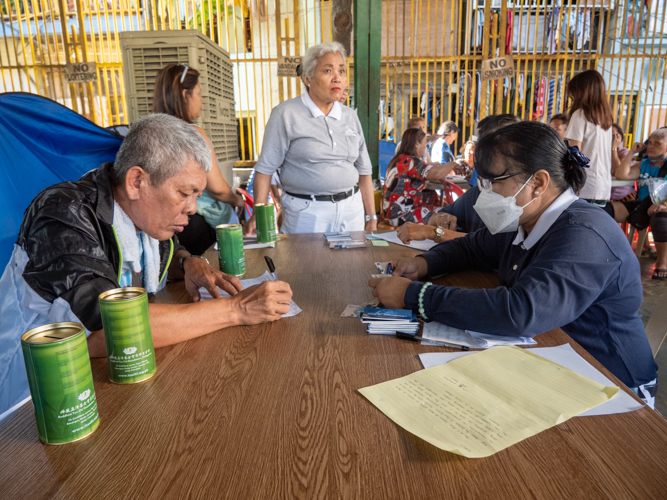 Representatives of families affected by the fire line up to get their claim stubs. 【Photo by Matt Serrano】