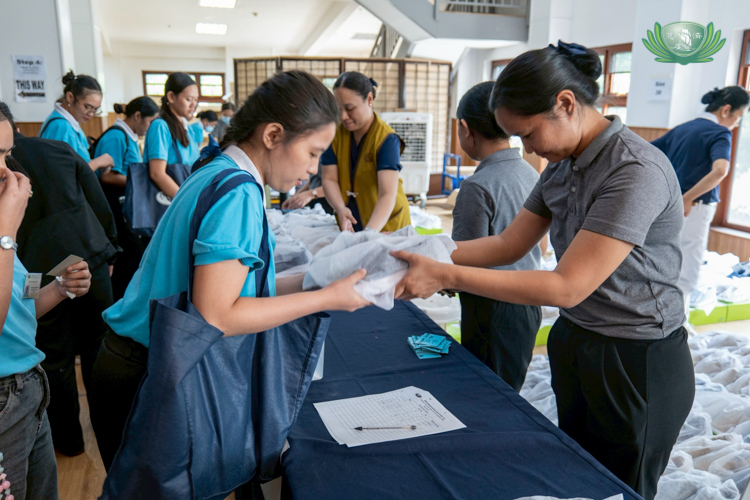 A Tzu Chi staff bows as she presents a scholar with her new pair of sneakers.