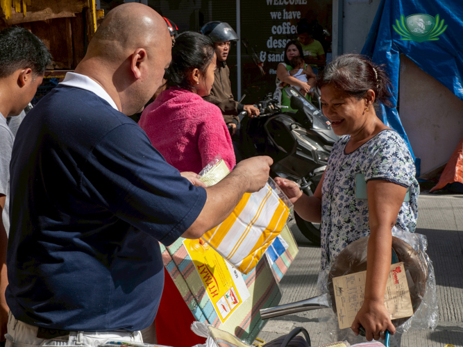 A resident smiles in gratitude as she receives relief goods from a Tzu Chi volunteer.