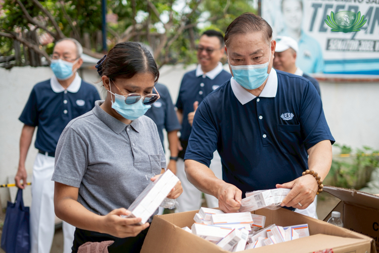 A Tzu Chi volunteer and staff member help organize medicines to be given to beneficiaries.