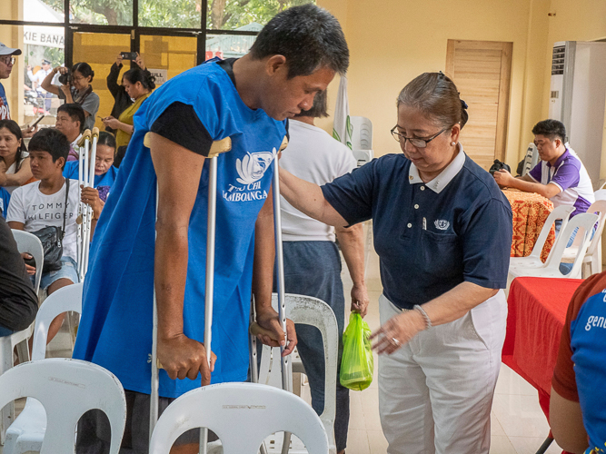A Tzu Chi volunteer assists a prosthesis recipient.