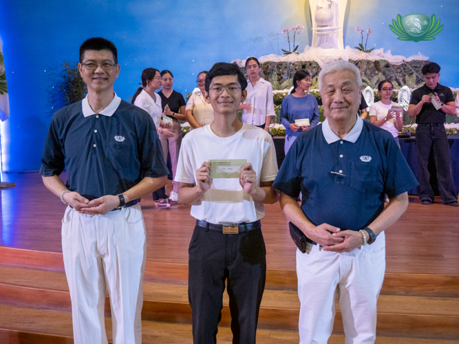 Aaron Kyle Genares (center), a scholar alumnus, is awarded a cash incentive and recognition by Taiwanese volunteer Cai Ming Mo (left) and Tzu Chi Foundation Philippines CEO Henry Yuñez (right), for graduating magna cum laude from the Philippine Normal University. 