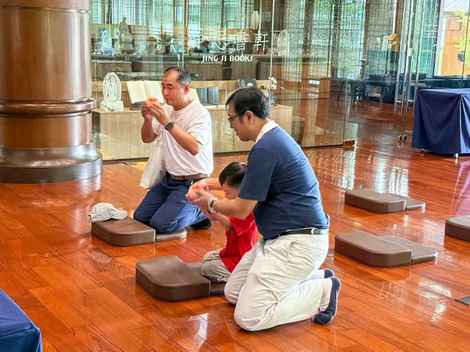 Nurturing spiritual awareness in the next generation, Tzu Chi volunteer Dewey Ong guides his son on the proper etiquette of offering prayer candles to the Buddha.