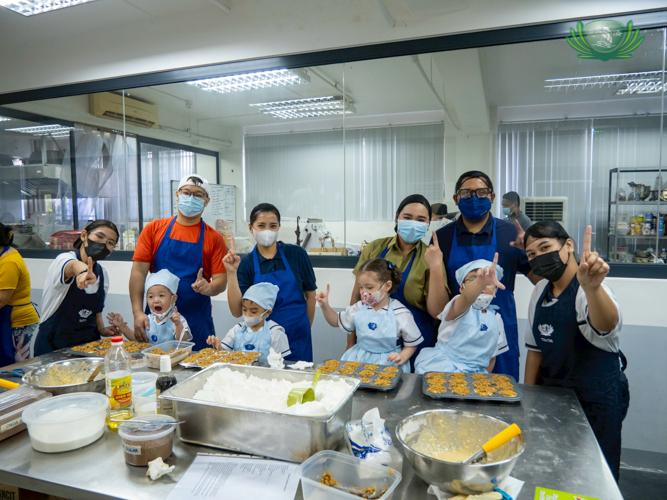 Teachers, parents, and young learners take a group photo after a successful baking activity. 