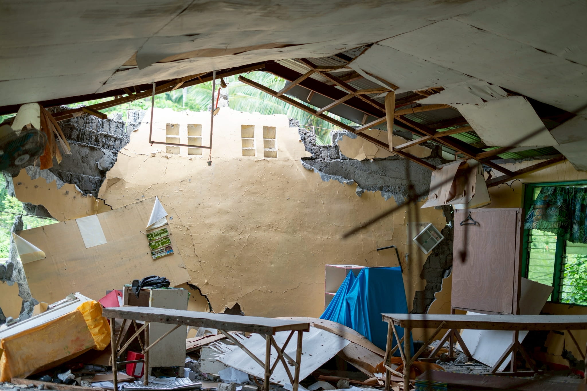 The earthquake caused the heavy concrete walls to crack and collapse, leaving the structure in ruins.