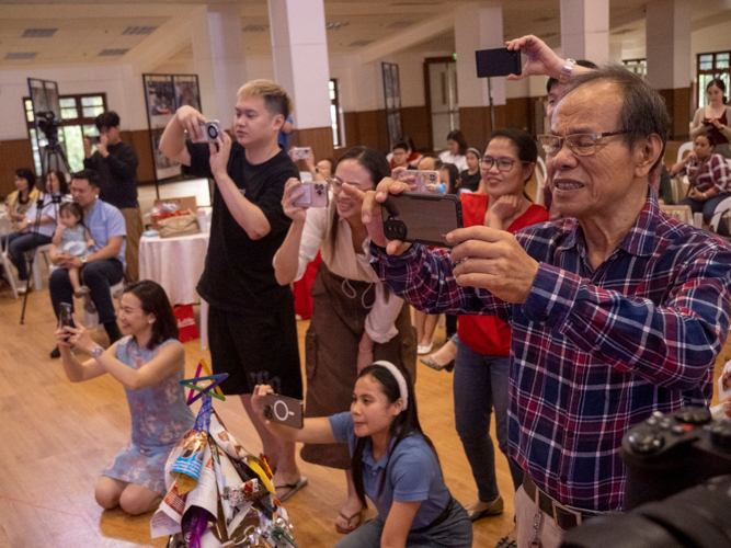 Proud parents and grandparents record the students’ performances.