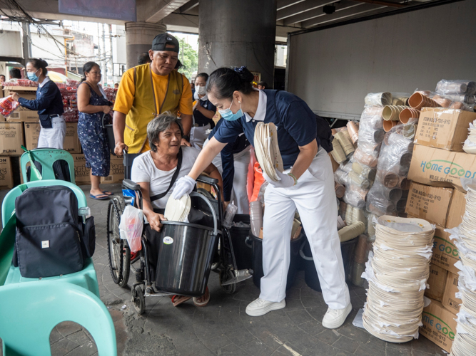 Living alone, Bienvenido Villamonte did not feel lonely, thanks to the compassion shown by Tzu Chi volunteers. A happy volunteer assists him as he receives plates included in relief items.