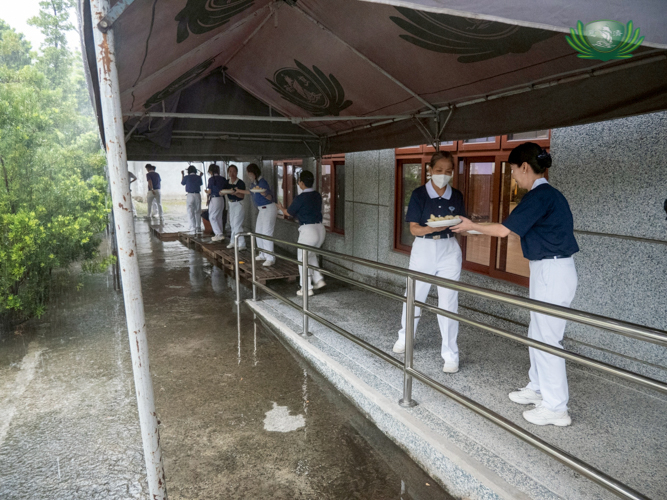 Volunteers help transfer snacks from Harmony Hall to Jing Si Hall during a downpour.