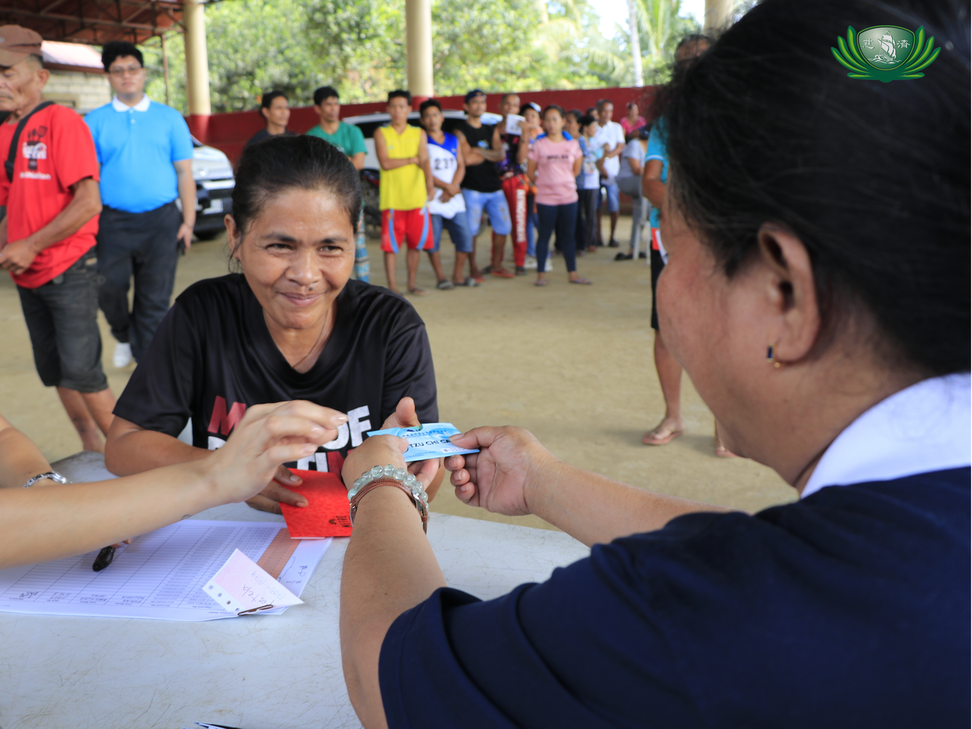 A beneficiary gratefully receives financial aid from Tzu Chi, stored in a Metrobank Pay Card.