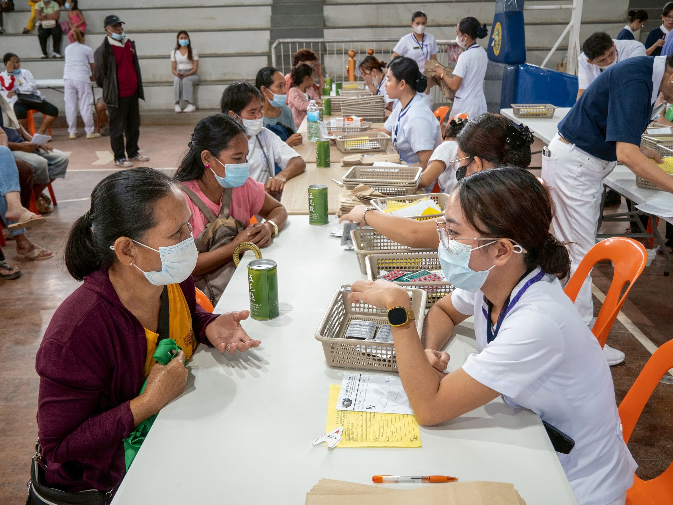 Patients with prescriptions receive free medication and a Tzu Chi coin can from volunteers at the pharmacy section. 