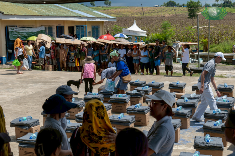 Many beneficiaries wait under the heat to receive their relief goods.