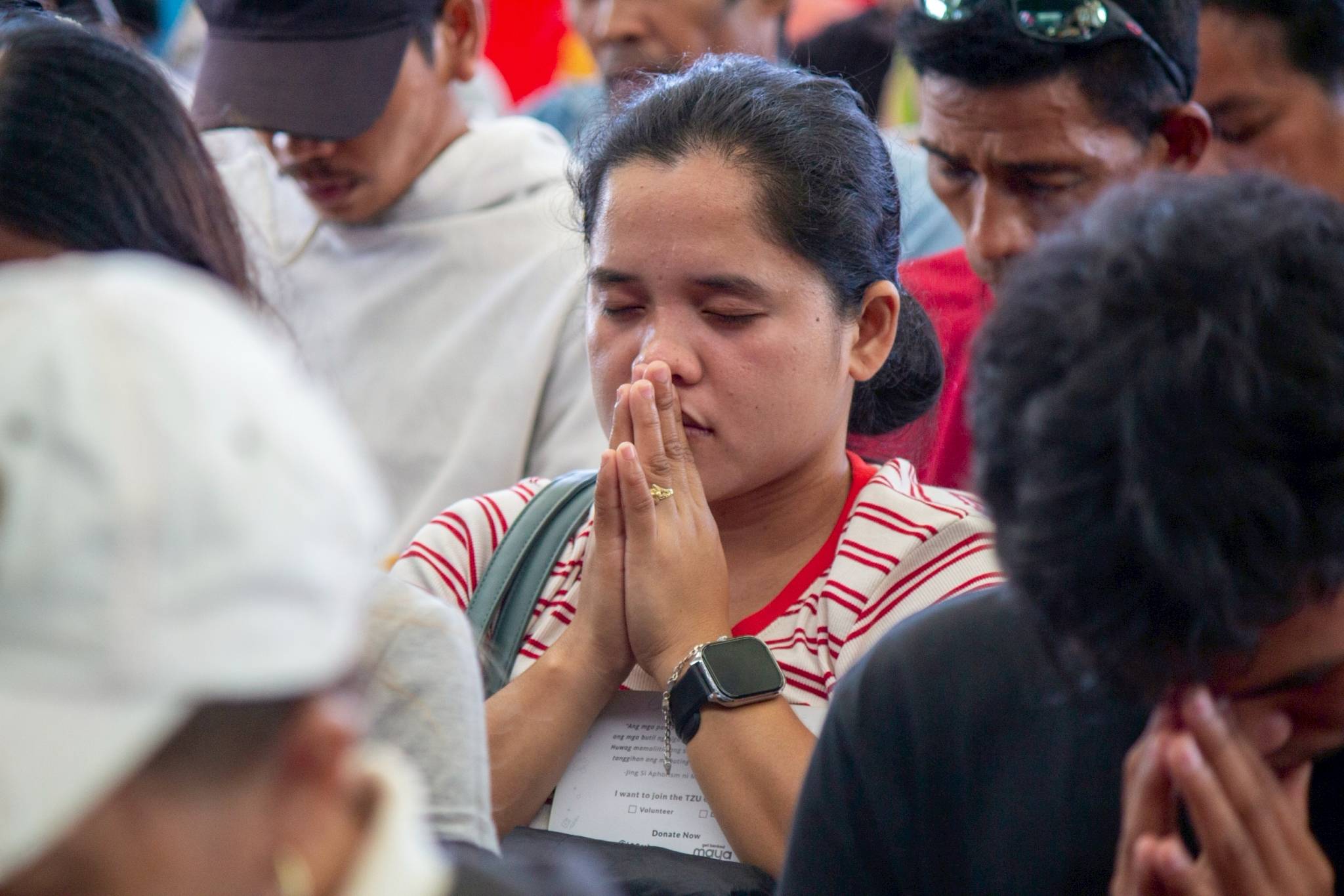 Beneficiaries observe a moment of silence, listening with heartfelt attention to the Tzu Chi prayer.