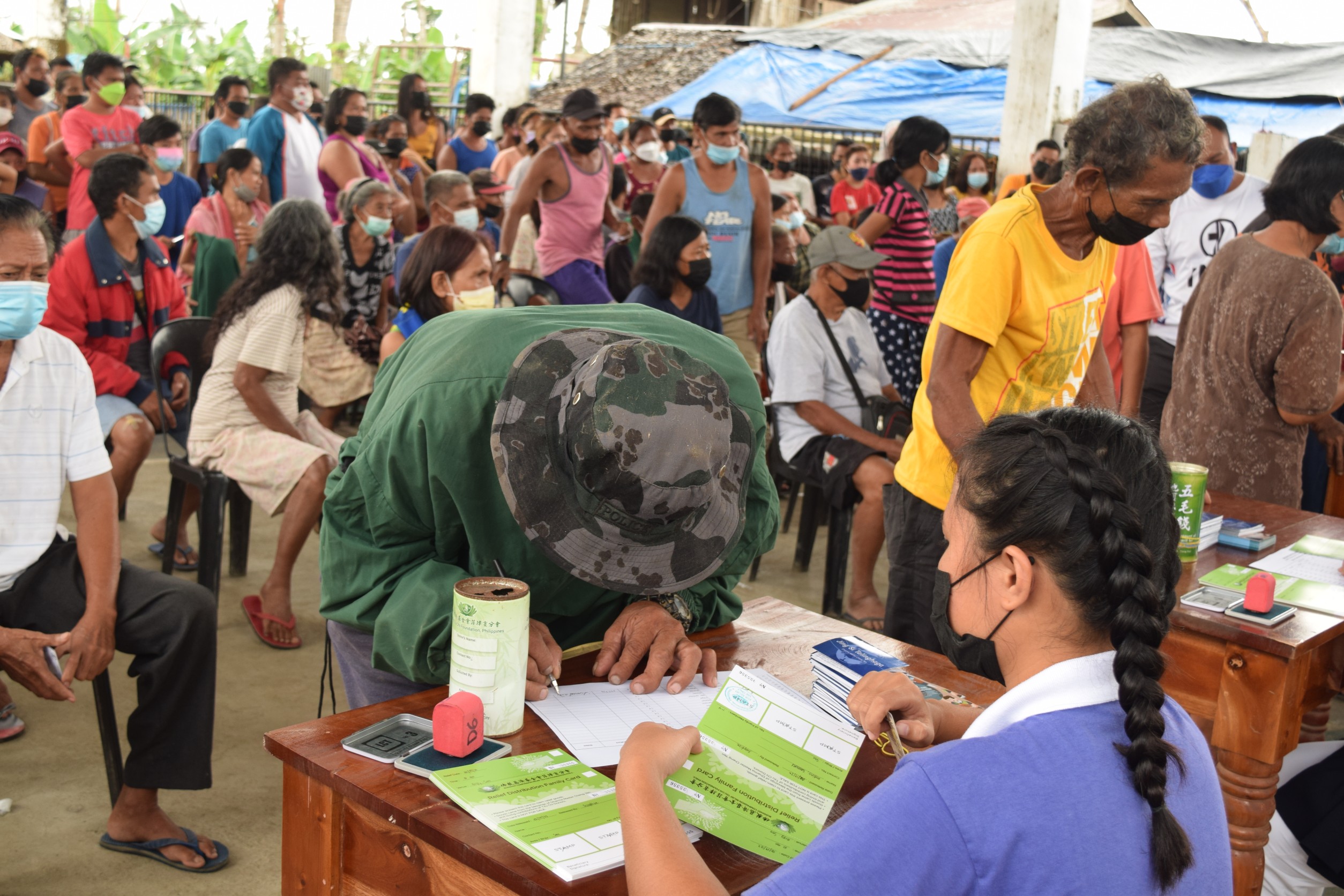 A man fills up a form to receive a stub that entitles him to claim GI sheets for his Odette-battered home. 