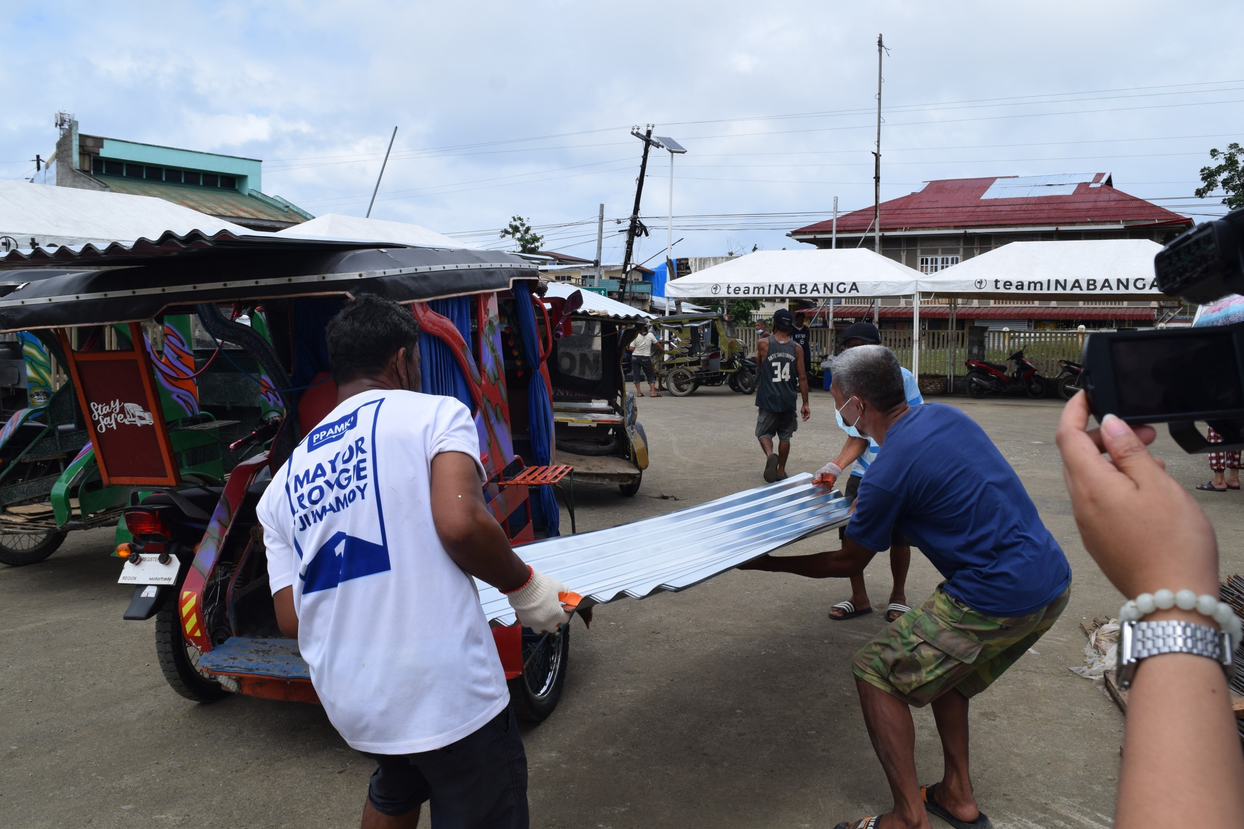 Beneficiaries in Inabanga pile up GI sheets on a tricycle. 