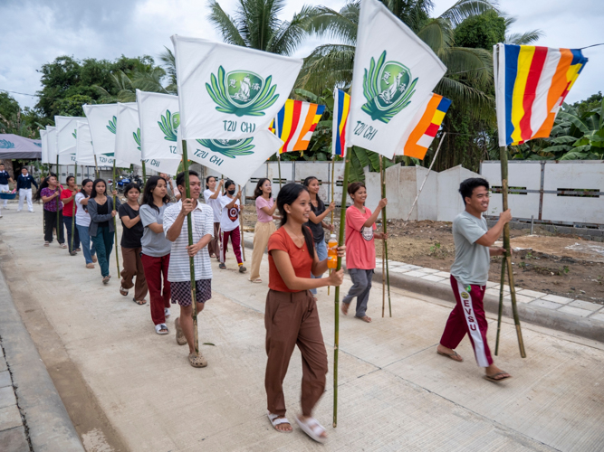 Tzu Chi scholars carry the flags of Tzu Chi Foundation to the gate in preparation for the turnover.