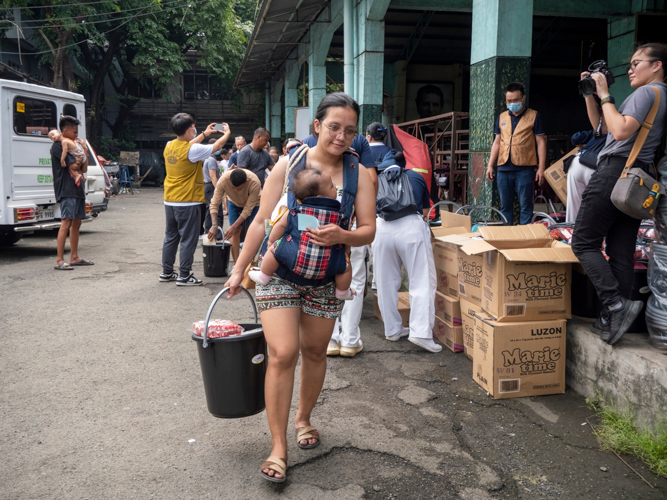 Luz Angelee Rojas, receives relief goods while carrying her baby.