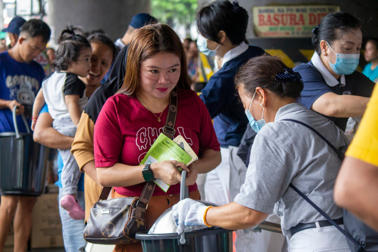 A beneficiary gratefully smiles as she receives relief goods for her family.