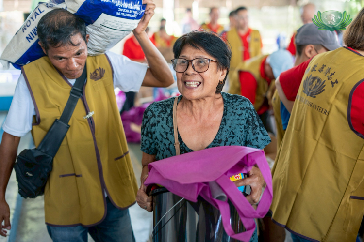 Beneficiaries from Singcang Airport, Bacolod City, leave the relief distribution venue smiling broadly, carrying groceries and sacks of rice.