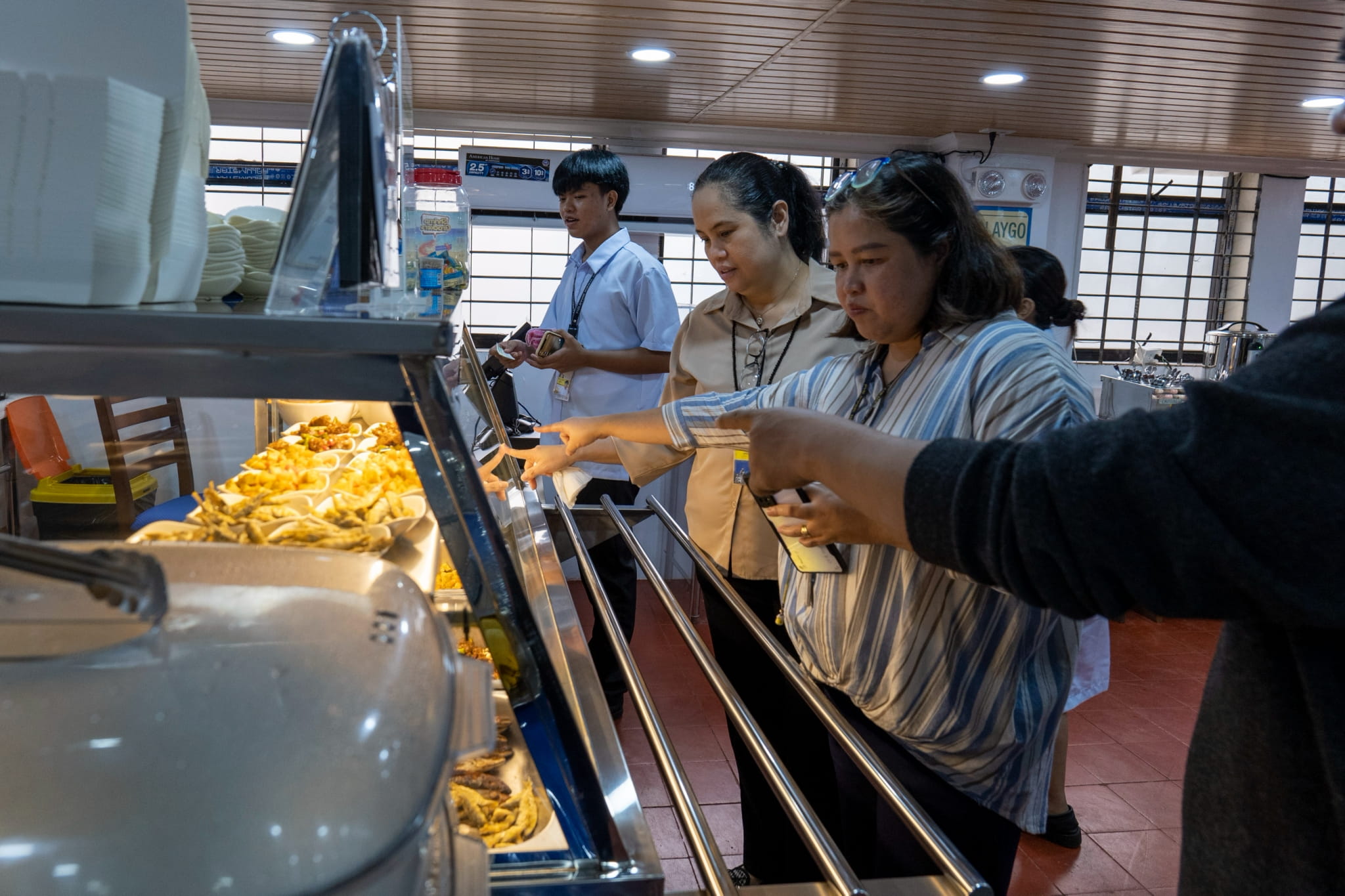 Jenny Malitao (center), the director of Administrative Services, was among the first customers to buy plant-based viands in the canteen.