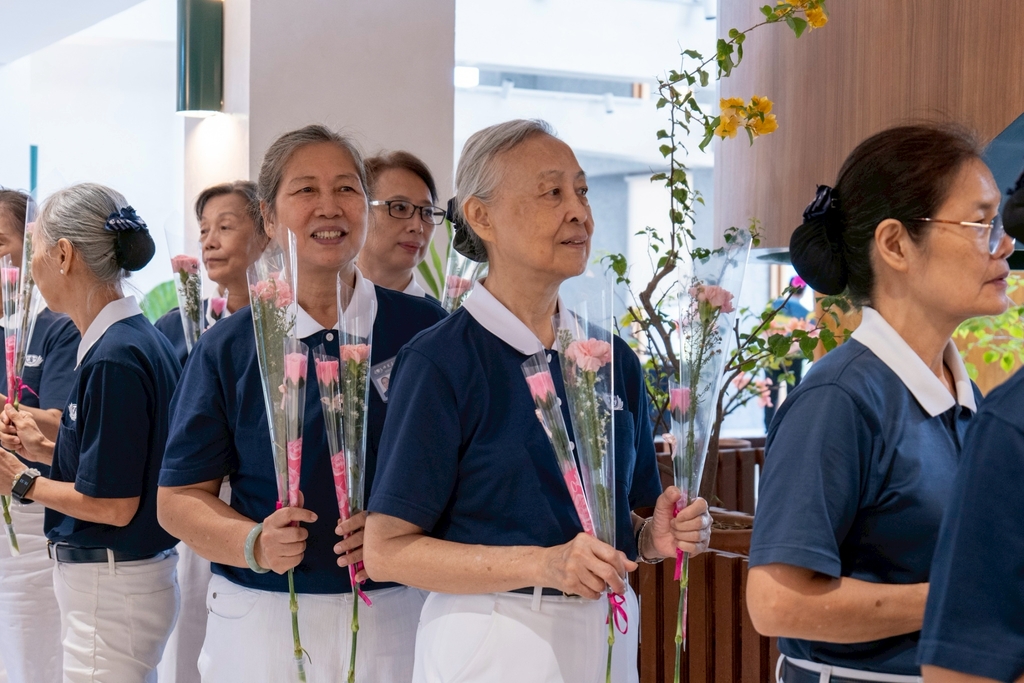 Volunteers line up to present seniors with flowers and an advanced Mother’s Day greeting.