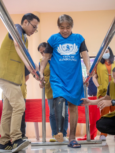 The prosthesis recipient smiles as he learns to walk with his new below-the-knee prosthesis.