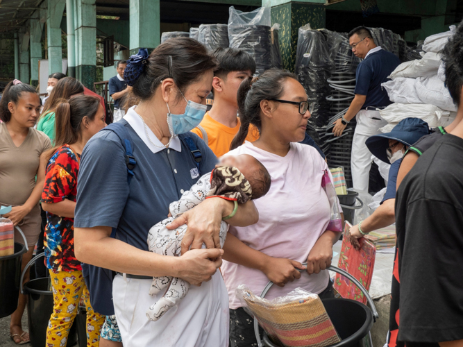 A Tzu Chi volunteer carries the beneficiary’s baby as she receives relief goods.