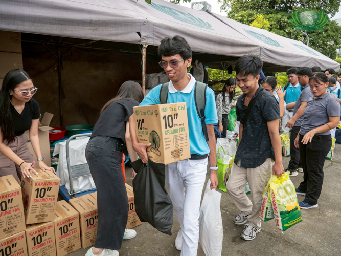 After sharing lunch, new Tzu Chi scholars lined up to receive grocery items, including 20 kg of rice, other essentials, and an electric fan.