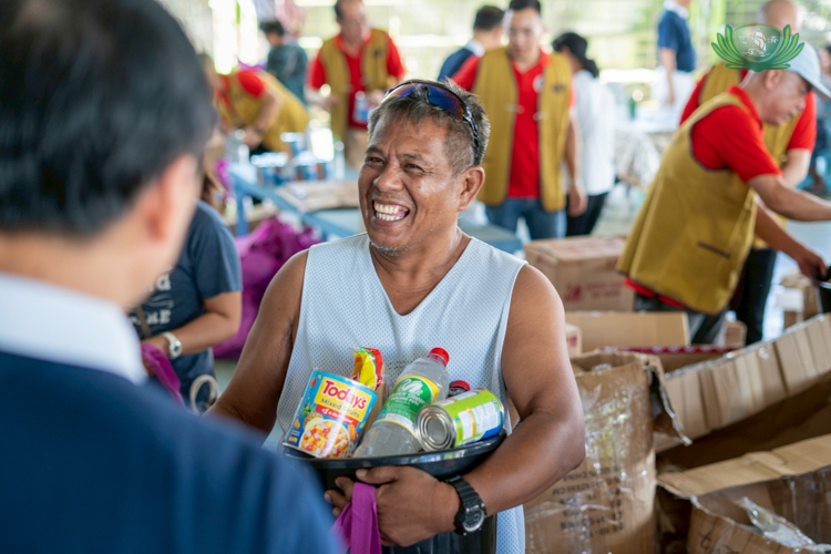 Beneficiaries from Singcang Airport, Bacolod City, leave the relief distribution venue smiling broadly, carrying groceries and sacks of rice.